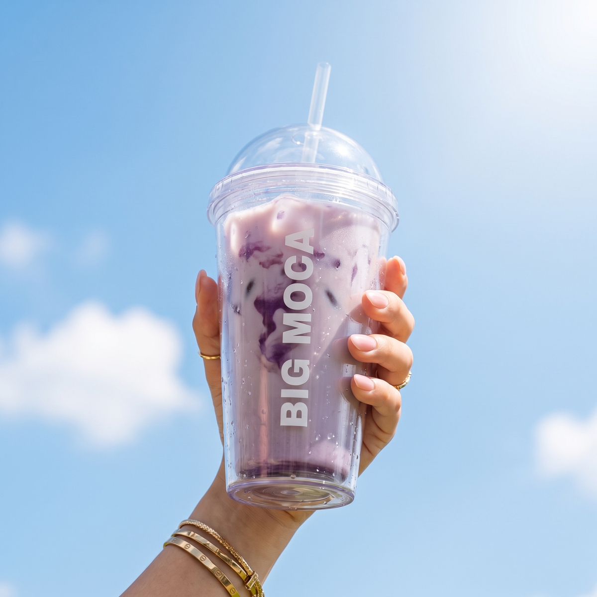 Iced ube latte in een Big Moca beker tegen een blauwe lucht